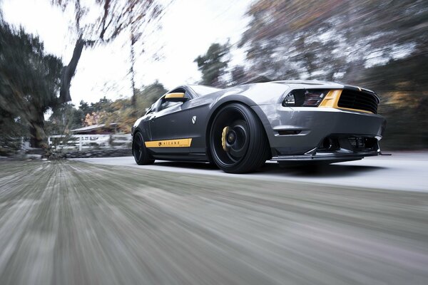 Muscle car srebrny Mustang pędzi z prędkością