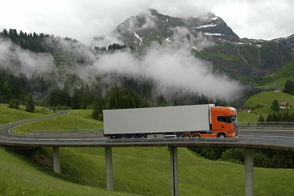 Orange tractor on the bridge among the green hills