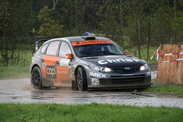 Coche deportivo, participante del Rally con barro y lluvia en medio de un bosque verde y hierba durante el día