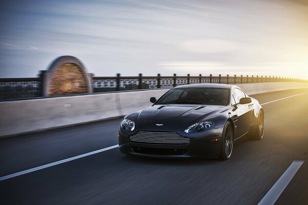 Black Aston Martin drives at speed on the highway