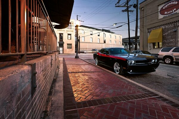 El auto Challenger negro está parado en la acera