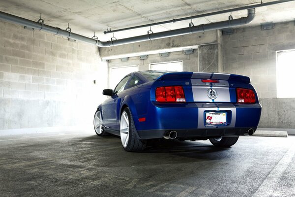 Auto blu Mustang su sfondo muro di mattoni