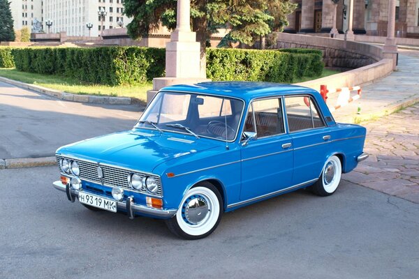 Voiture soviétique VAZ sur fond de pelouse verte avec arbre et gris haut bâtiment et