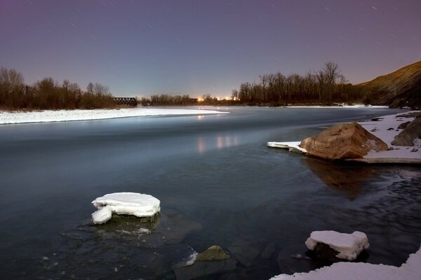 Inverno sul fiume con neve e pietre