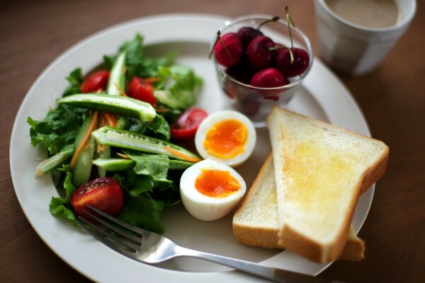 Colazione a base di uova, pane tostato e insalata su un piatto bianco