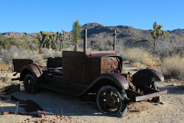 A rusty abandoned retro car in the desert