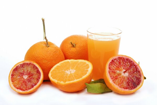 Oranges and grapefruits next to a glass of orange juice