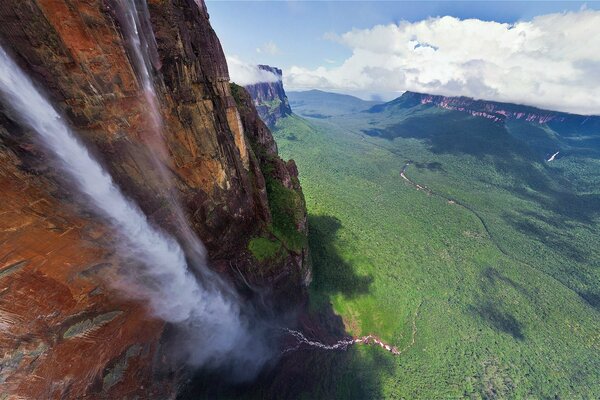 High waterfall with mountains, greenery and clouds