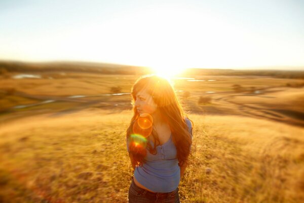 Mädchen auf dem Hintergrund der Sonne im Feld