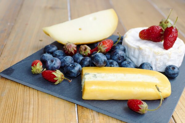 Fromage à côté des bleuets et des fraises sur une serviette