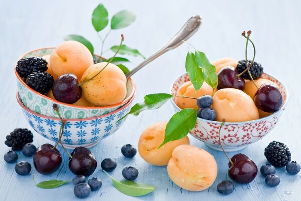 Albaricoques, cerezas, moras y arándanos en platos