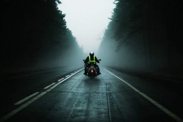 A motorcycle with a man riding on the road