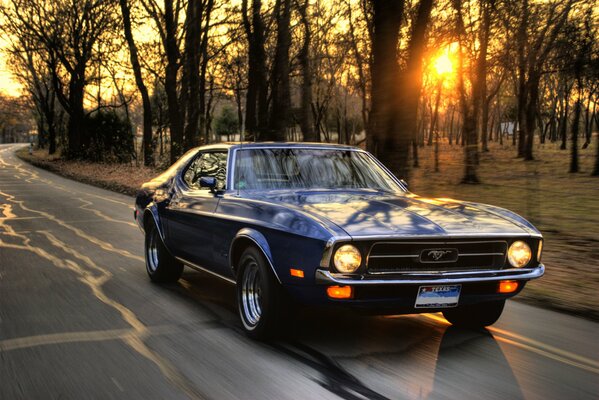 Voiture ford Mustang sur la route au coucher du soleil