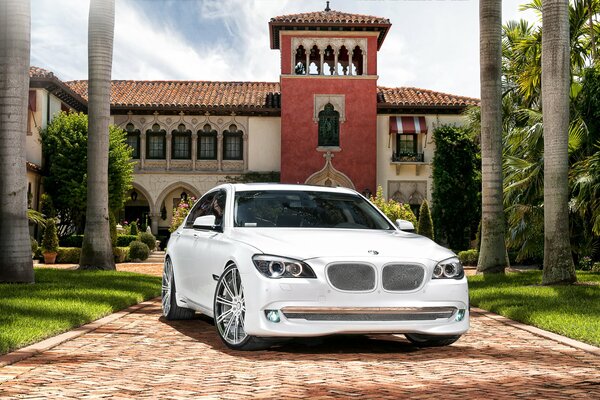 BMW serie 7 blanco como la nieve en el fondo de una mansión de lujo