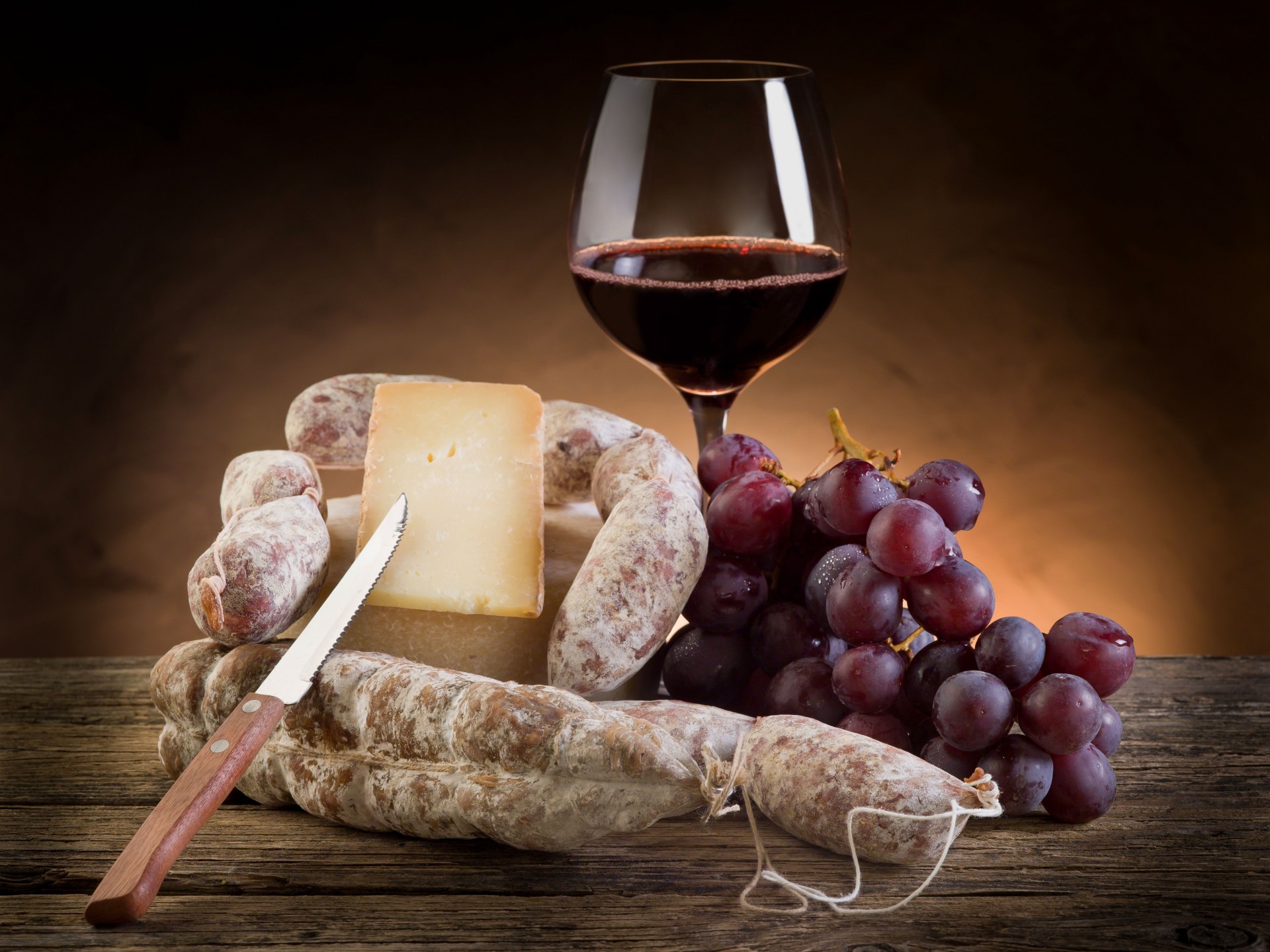 knife grapes sausages glass wine cheese