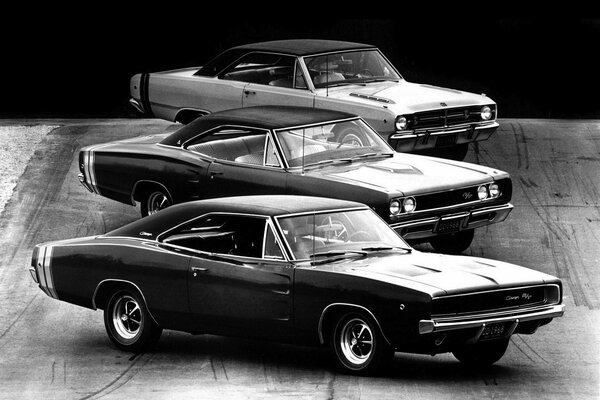 Tre muscle car retrò su sfondo scuro