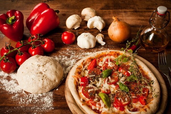 Pizza con tomates y pimientos en una mesa de madera