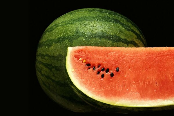 Schwitzende Wassermelone auf schwarzem Hintergrund mit abgeschnittenem Stück