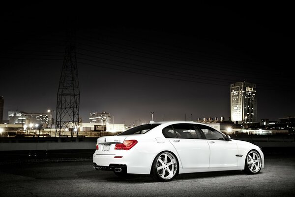 Белый BMW на фоне городского пейзажа. Ночные огни
