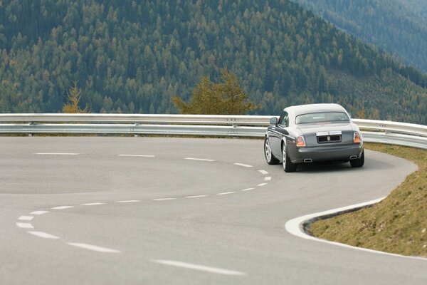 Rolls Royce sur un virage serré au milieu des montagnes vertes