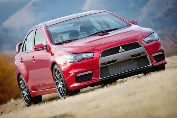 Prototipo rojo Mitsubishi en la hierba a lo largo de la carretera