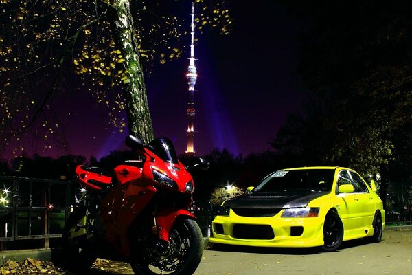 A motorcycle and a car are on the road at night