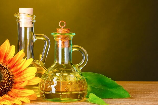 Eine Glasflasche mit Sonnenblumenöl steht auf einem Holztisch