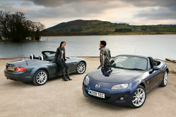 Two drivers standing near cars on the river bank