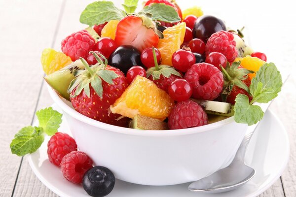 Fruit salad in a large bowl with a spoon and mint