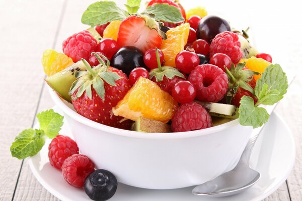 Salade de fruits dans un grand bol avec cuillère et menthe