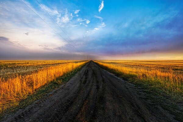 Route dans le champ sur fond de beau ciel