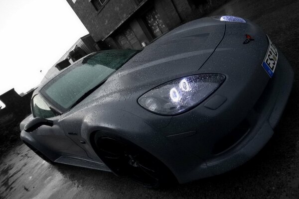 A black car on a gray road in the rain