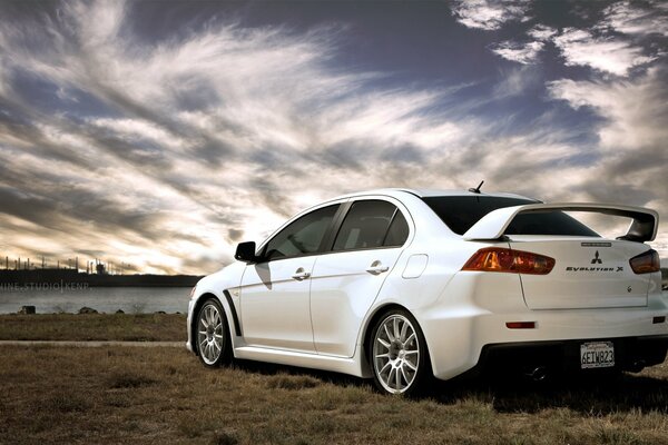 Un Mitsubishi blanco se encuentra en medio de hermosas nubes y un río