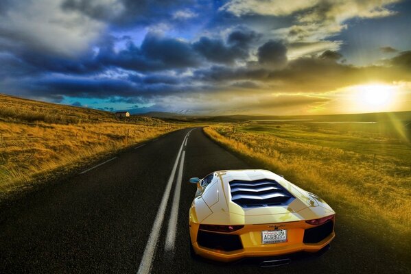 Ein gelber Lamborghini fährt die Strecke entlang. Rund um die Landschaft mit Feldern bei Sonnenuntergang