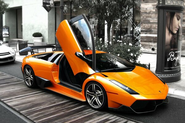 Lamborghini naranja con puerta abierta en la calle gris