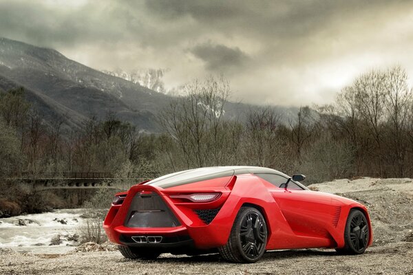 Voiture inhabituelle rouge se trouve derrière la ville sur fond de montagnes