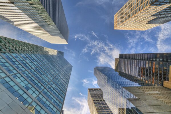 Altos rascacielos de nueva York que se extienden hacia el cielo, reflejando nubes en los cristales