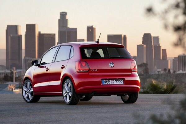 A red car is driving on the roads of the city