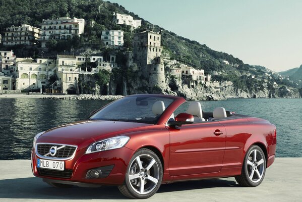 Coche rojo Volvo C70 convertible en el fondo de la ciudad