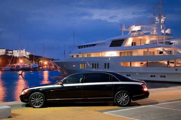 Voiture noire de luxe sur fond de grand yacht blanc