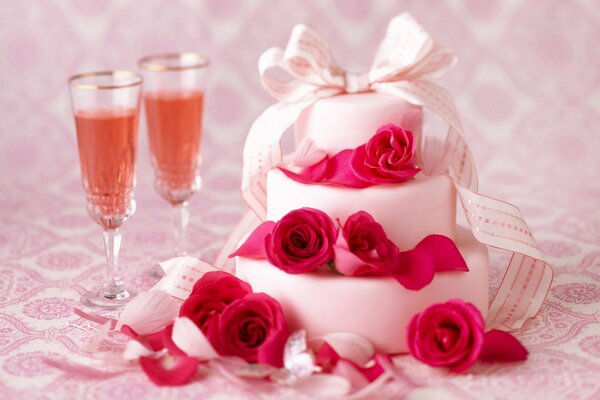 A luxurious cake with roses and a bow and two glasses of champagne