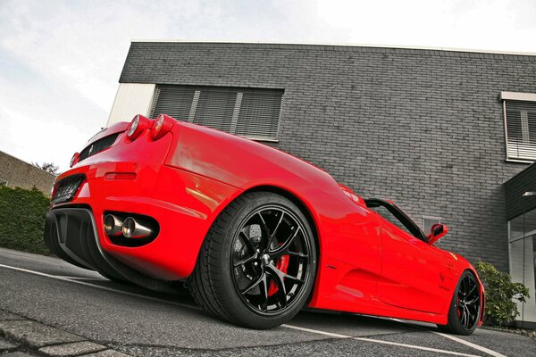 The back of a red Ferrari parked near the house