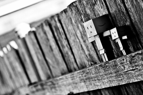 Dark figures in the form of boxes pressed against the fence