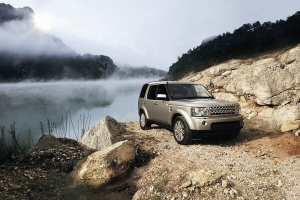 Range rover Auto steht in den Bergen auf Nebel und Fluss