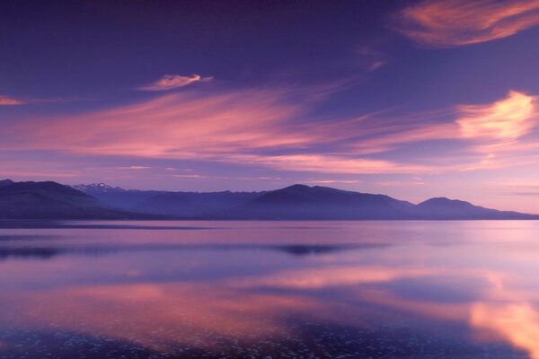 Reflejo de las cimas de las montañas y las nubes en el lago