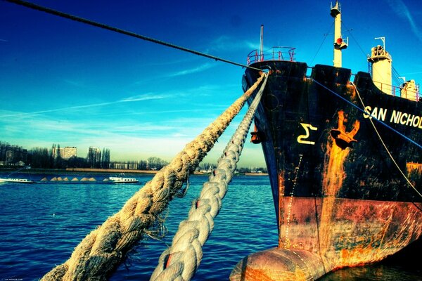 The black ship moored with ropes to the pier