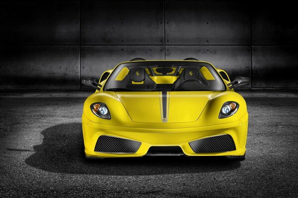 A yellow sports car against a gray wall