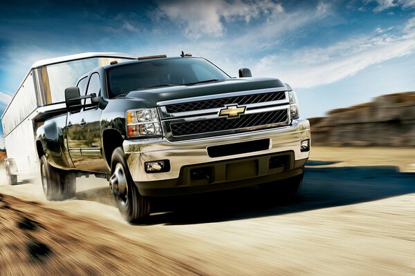 Chevrolet at speed with a trailer against the sky