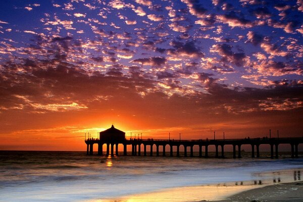 El puente se encuentra en el fondo de la puesta de sol junto al mar