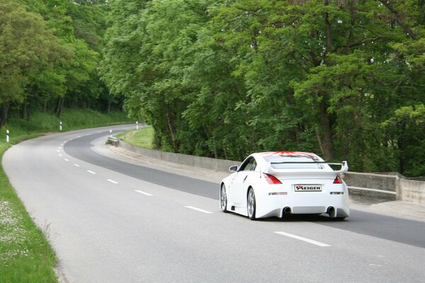 A beautiful white car is driving on the road